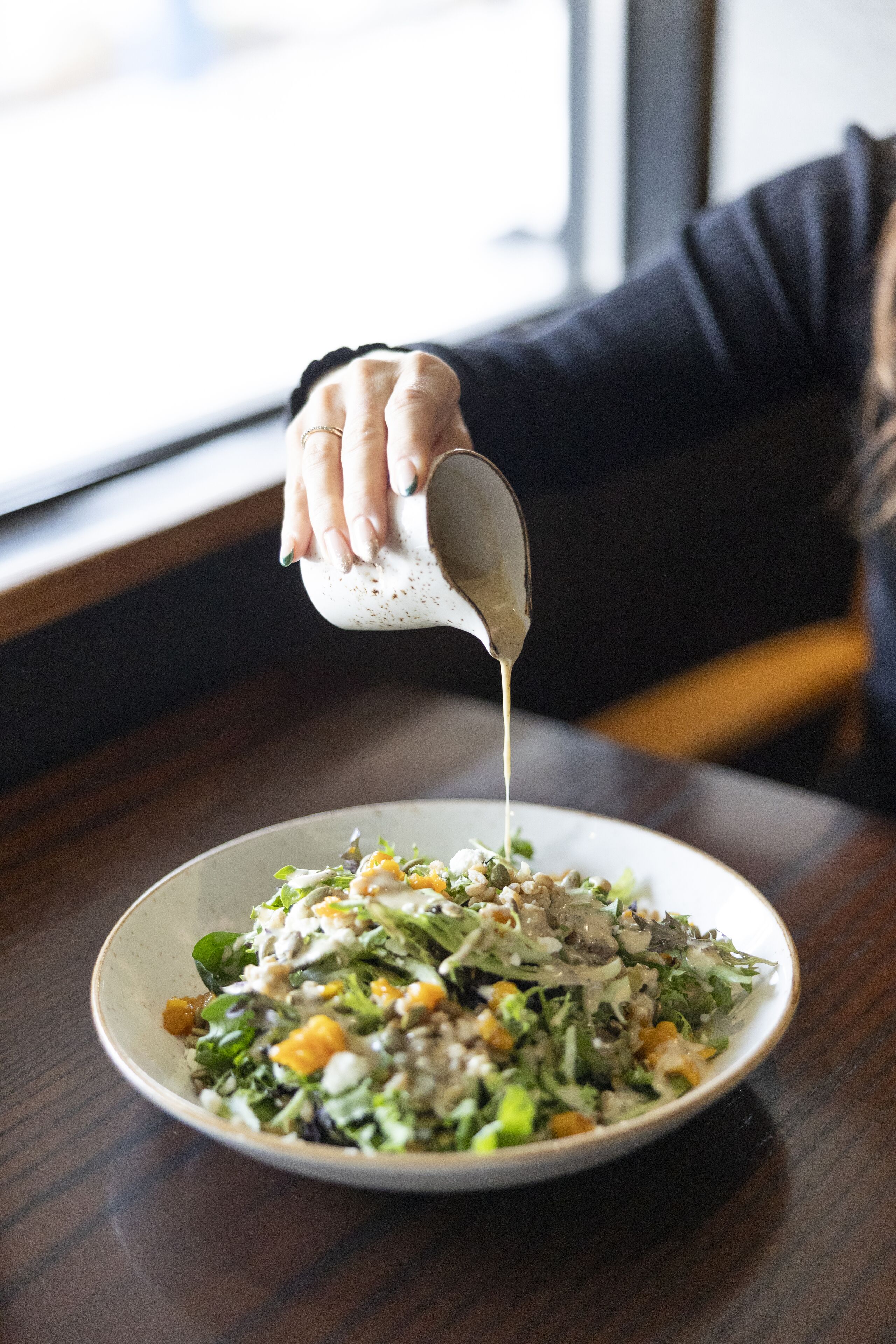 Ein Salat wird mit Dressing übergossen.