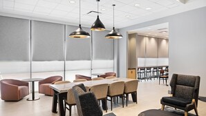A modern conference room with a round table, multiple chairs, and pendant lighting. - Radisson Hotel Salt Lake City Downtown (Salt Lake City)