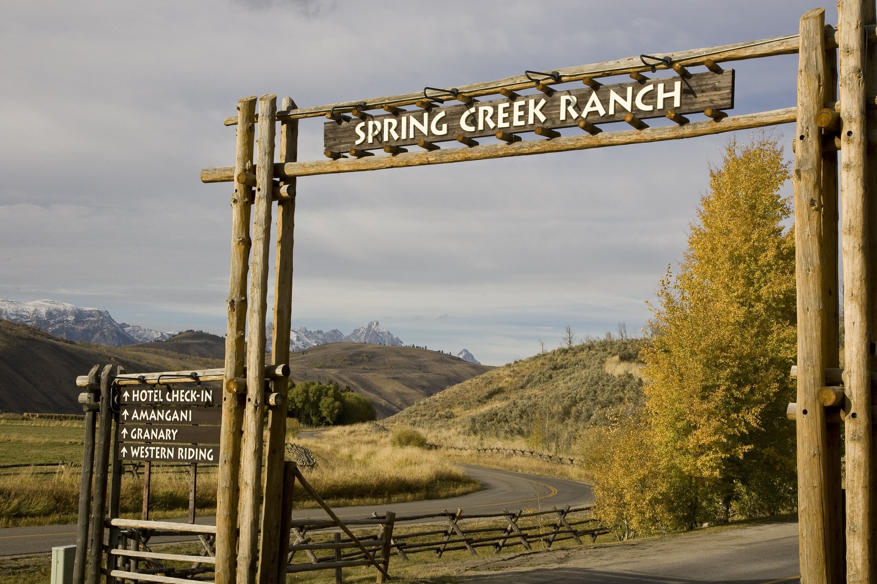 A wooden sign with 'SPRING CREEK RANCH' and directional arrows pointing to 'HOTEL CHECK-IN', 'AMANGANI', 'GRANARY', and 'WESTERN RIDING'.