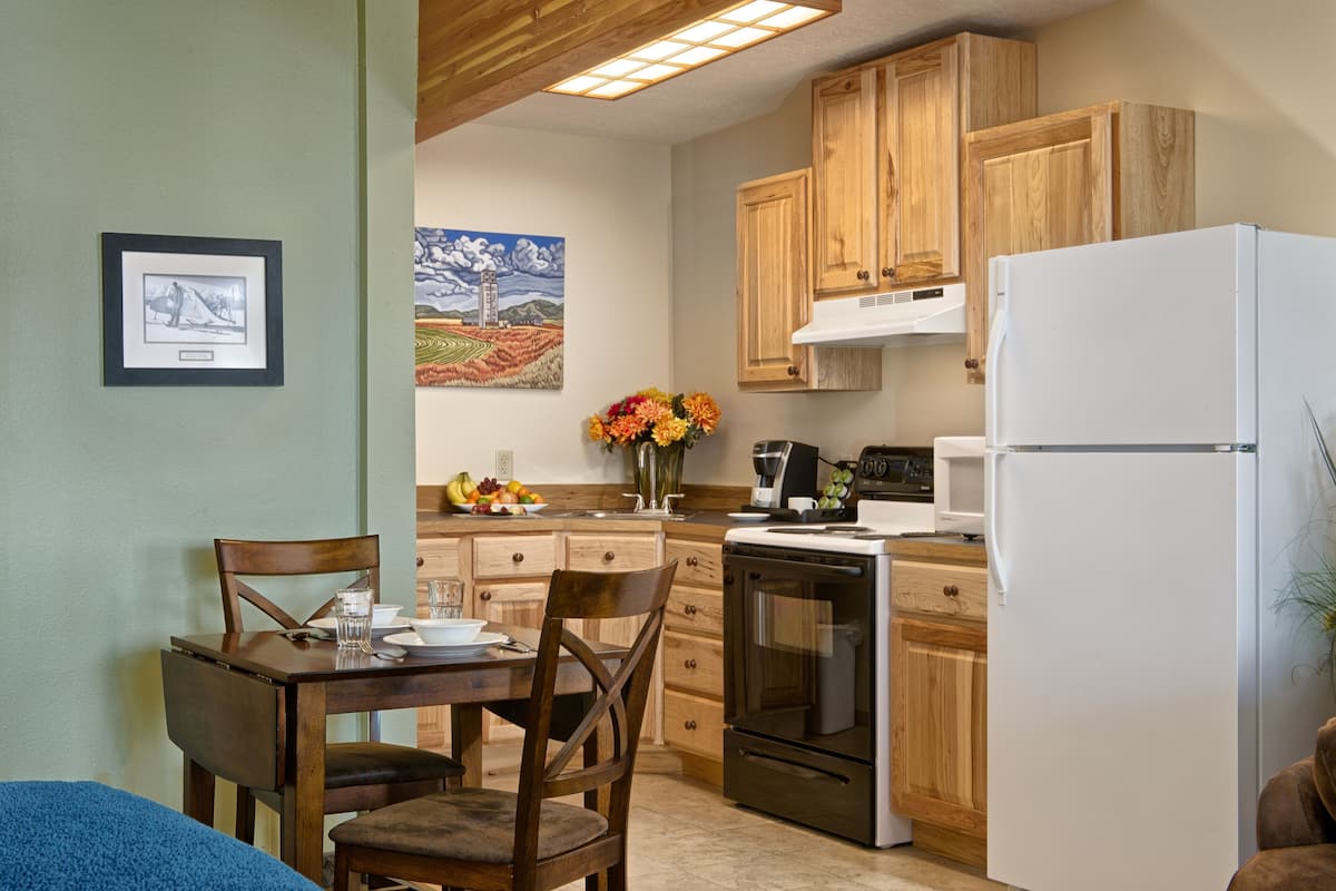 A kitchen with wooden cabinets, a white refrigerator, and a dining area with a table and chairs.