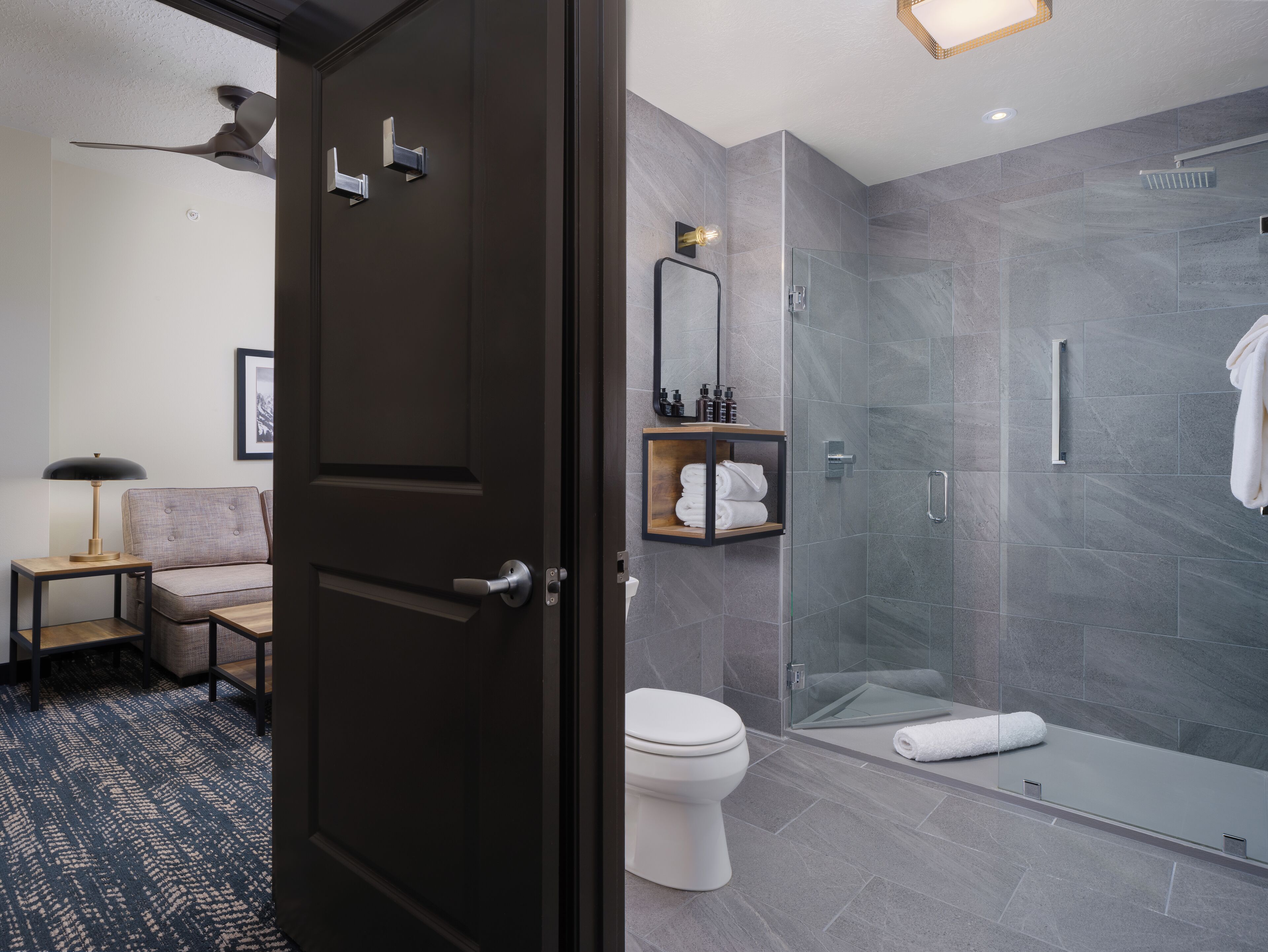 A modern bathroom with a glass shower enclosure, a toilet, and a vanity with a mirror.