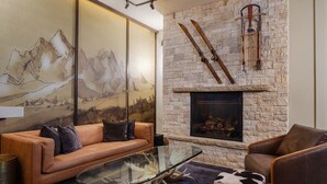 A modern living room with a stone fireplace, leather sofas, and a glass coffee table. - The Rockwell Inn (Jackson)