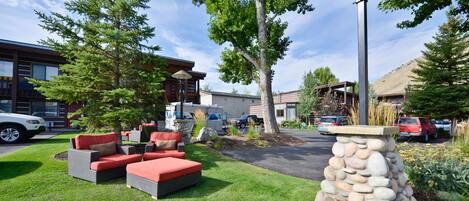 A well-maintained outdoor area with a stone pillar, red and grey outdoor furniture, and a paved walkway.