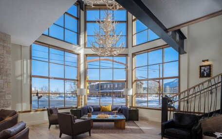 A spacious living room with large windows, a chandelier, and a view of a snowy landscape.