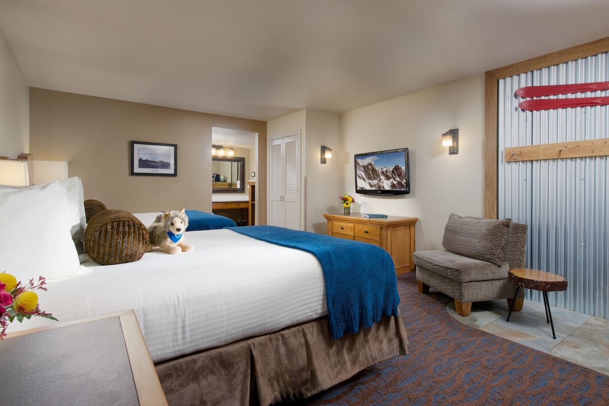 A hotel room with a bed, a chair, a small table, a dresser, a mirror, and a picture on the wall.