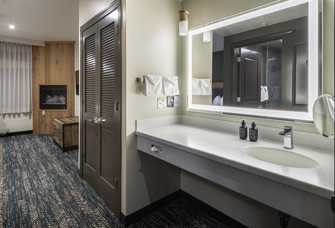 A modern bathroom with a large mirror, a sink, and a towel rack.