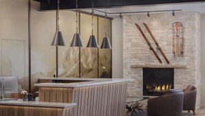 A modern kitchen with a central island, pendant lighting, a stone fireplace, and a seating area with leather chairs. - The Rockwell Inn (Jackson)