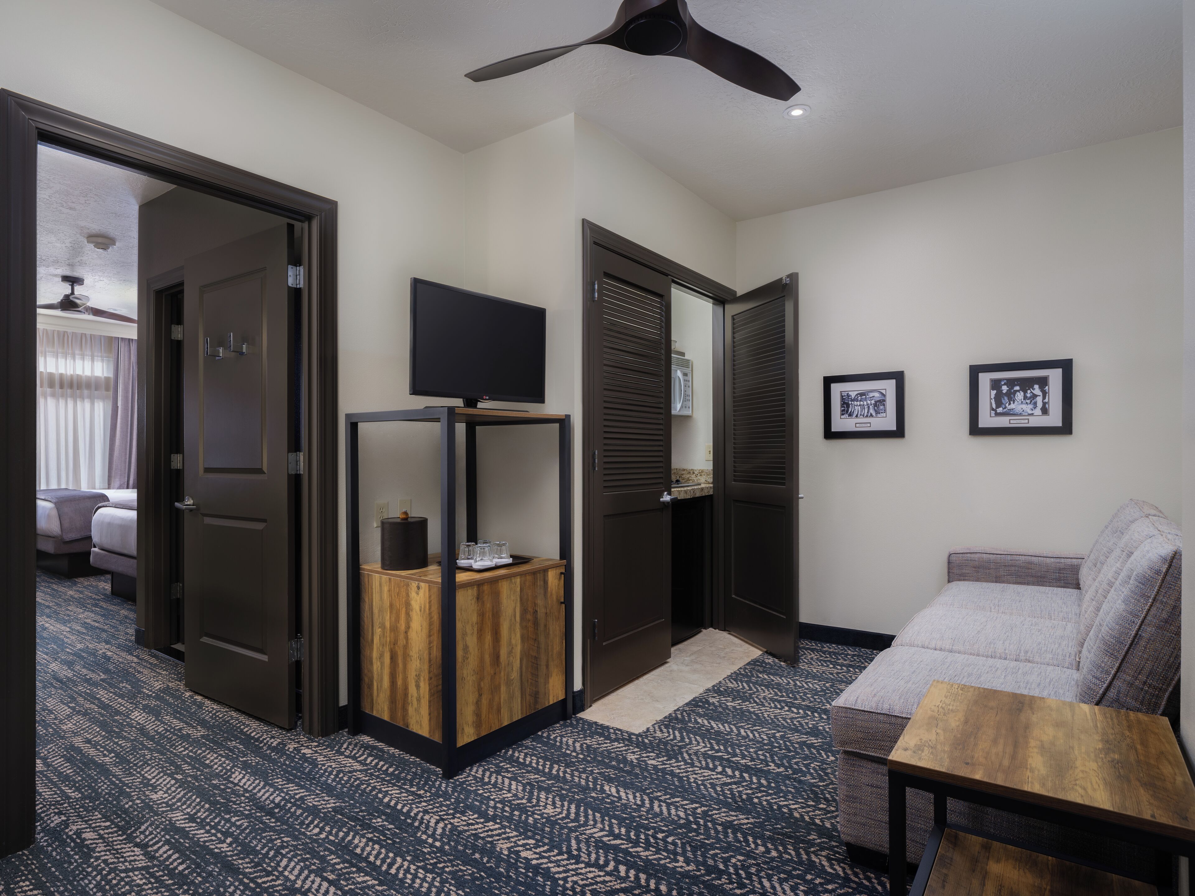 A hotel room with a bed, a TV on a stand, a small wooden table, and a sofa.