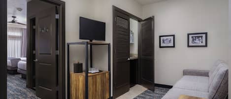 Une chambre d’hôtel avec un lit, un téléviseur posé sur un meuble, une petite table en bois et un canapé.