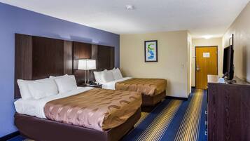 Habitación de hotel con dos camas, un escritorio, un televisor y una puerta.