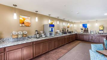 Una cocina de hotel con encimera de mármol, máquinas de café y un refrigerador.