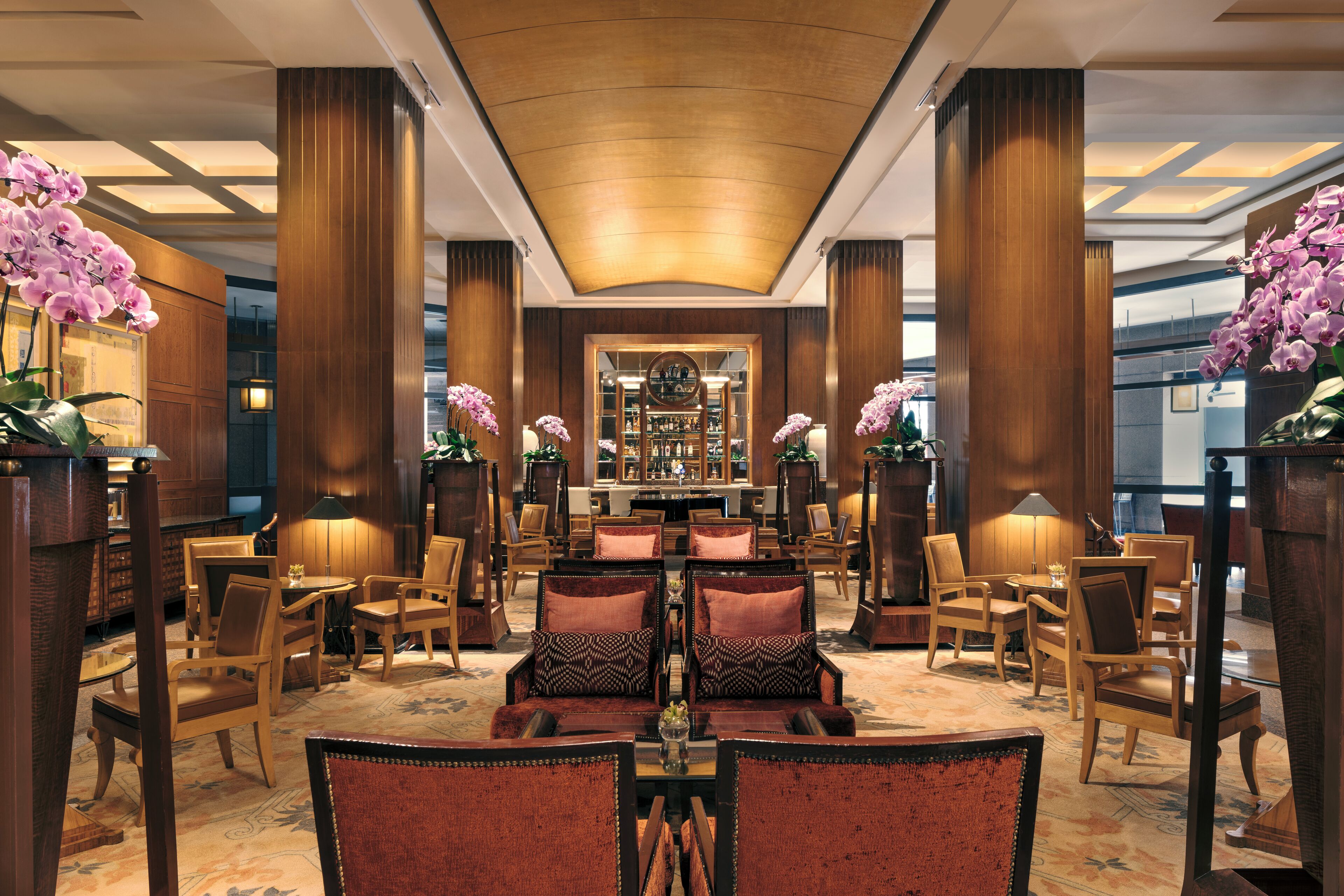 Un lobby espacioso con techos altos, grandes columnas de madera y una zona de bar central.
