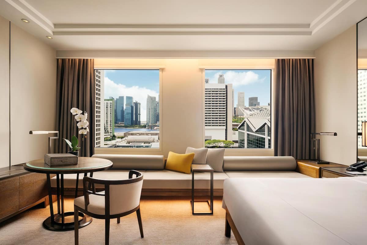 Una habitación de hotel con un ventanal grande, un sofá, una mesa de comedor y una cama.