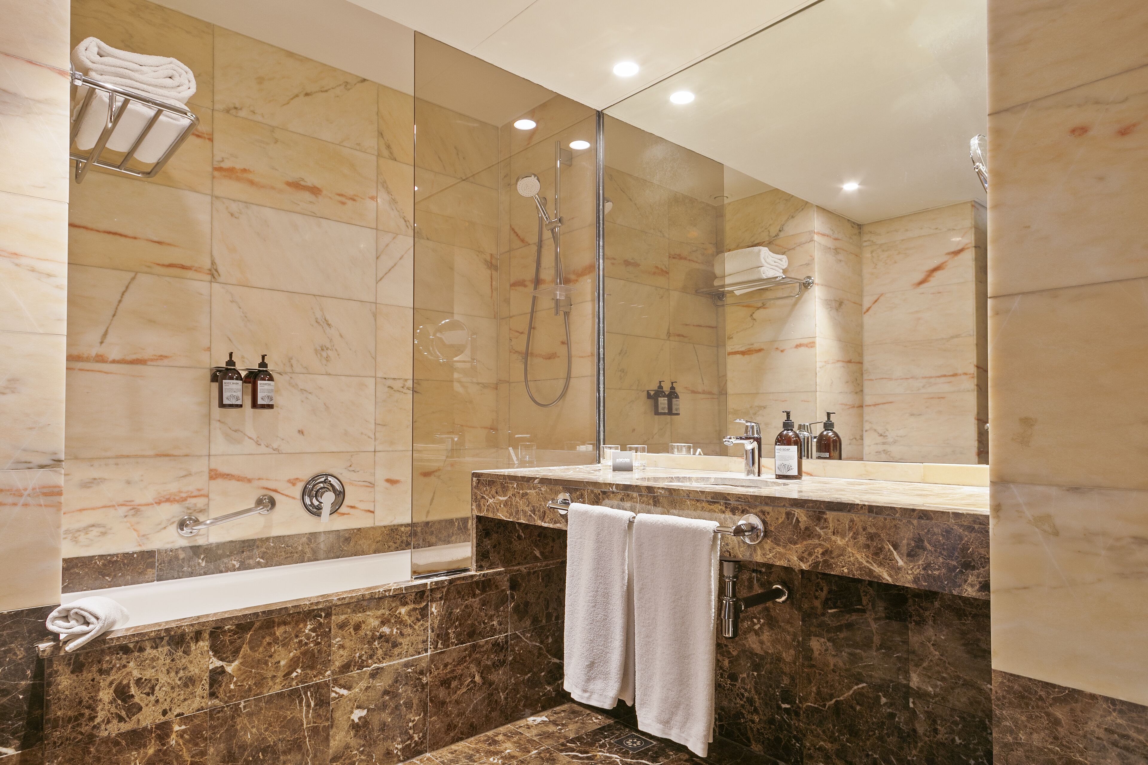 Een moderne badkamer met een marmeren wastafelmeubel, een douche met glazen wanden en een grote spiegel.