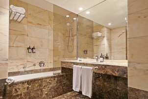 A modern bathroom with a marble vanity, a glass-enclosed shower, and a large mirror.