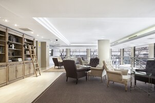 Uma biblioteca moderna com estantes, assentos confortáveis e grandes janelas.