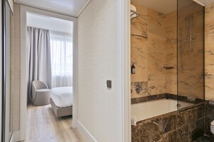 A modern bathroom with a glass-enclosed shower, a bathtub, and a toilet.