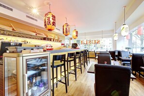 L’intérieur d’un restaurant, avec un bar, des tables et une vue sur l’extérieur par les fenêtres.