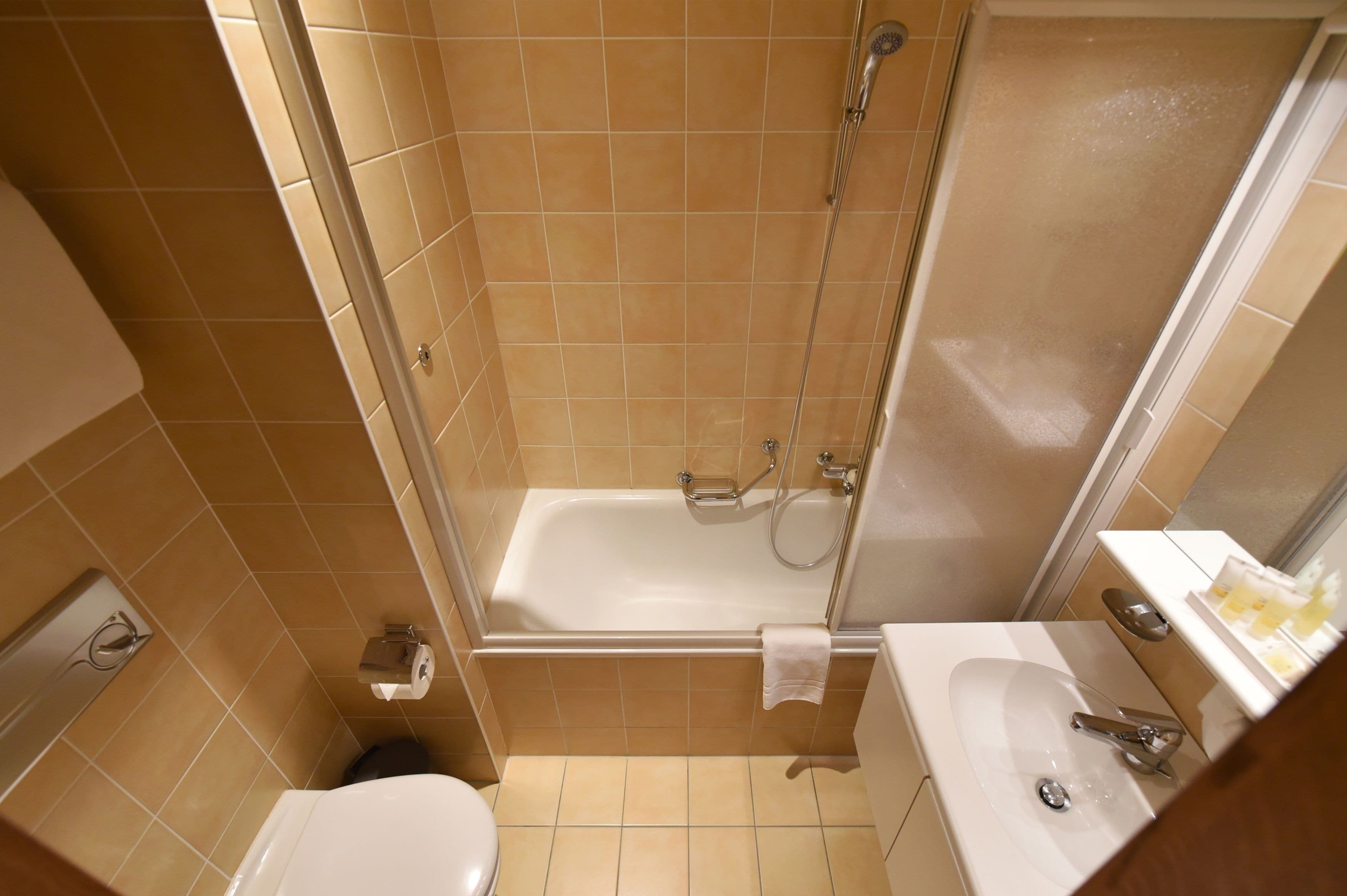 Un baño pequeño con bañera, inodoro y lavamanos.