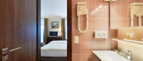 A hotel bathroom with a sink, mirror, and shower.