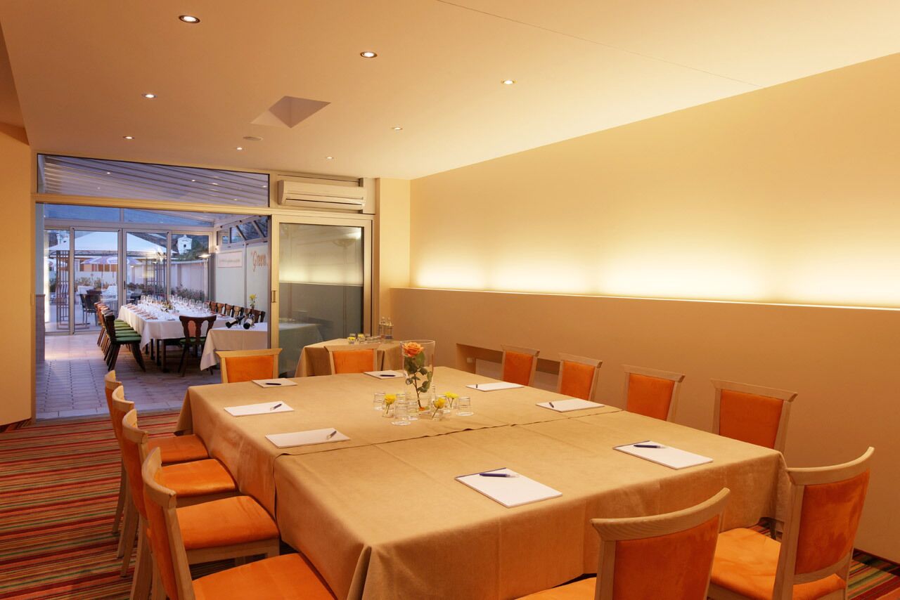 A conference room with a large table, orange chairs, and a glass partition.