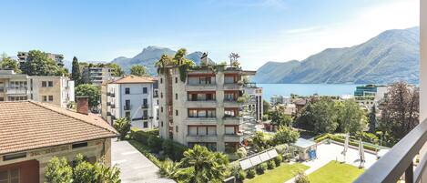 Zona residencial con edificios, vista despejada de un lago y montañas al fondo.