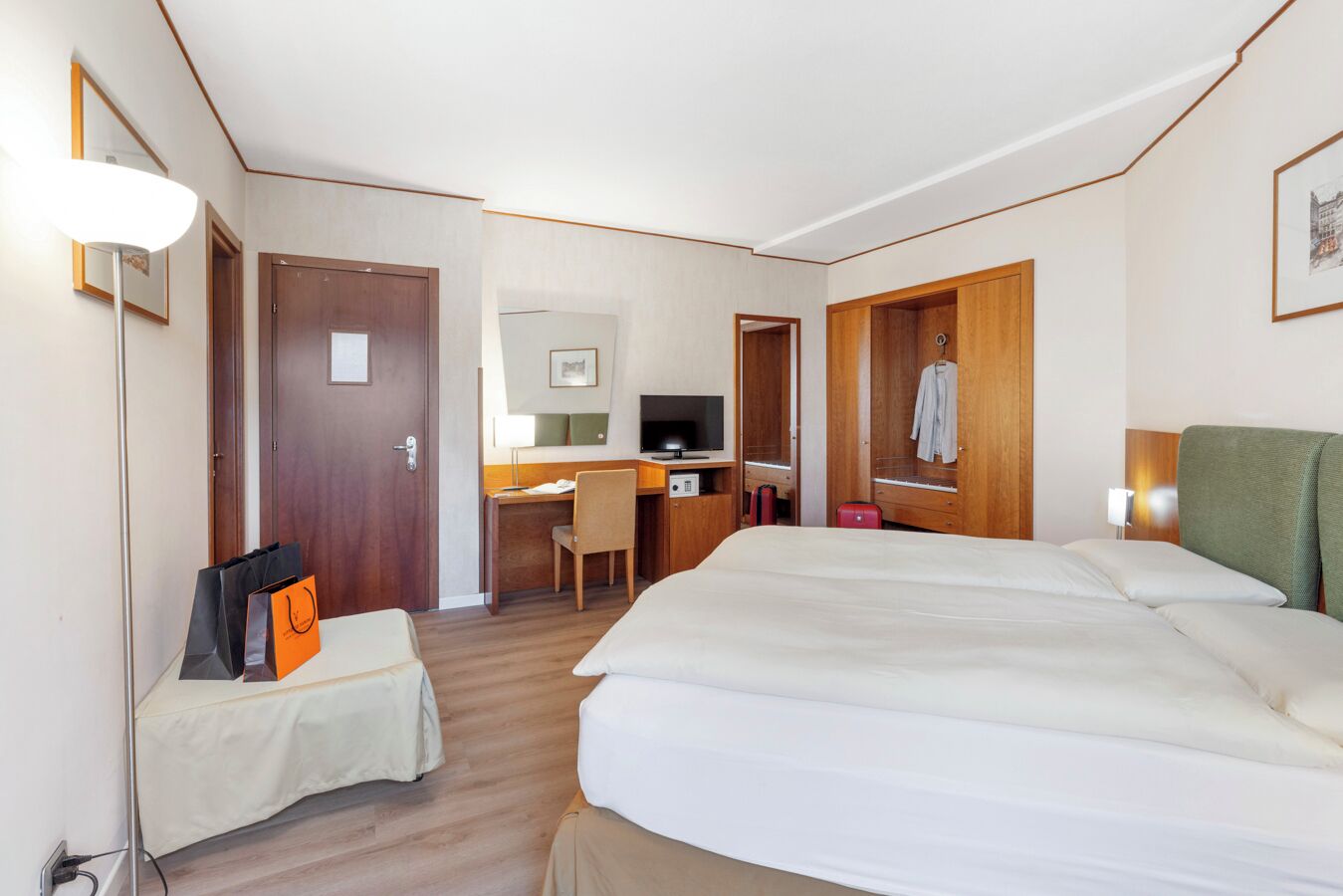 Une chambre d’hôtel comprenant un lit, un bureau, une chaise, une télévision et une armoire.
