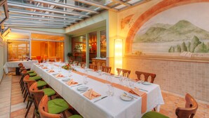Una larga mesa de comedor preparada para una comida en un restaurante con vista a un mural y un muro de azulejos.
