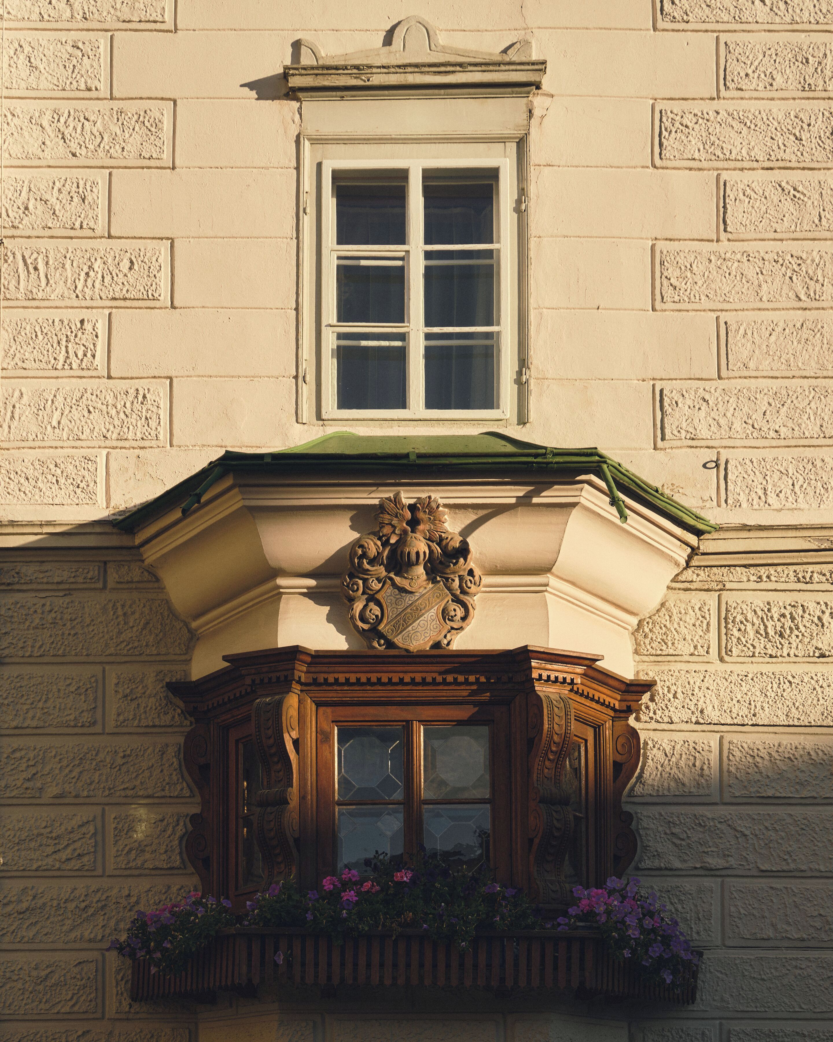 A building facade with a window, decorative cornice, and a flower box.