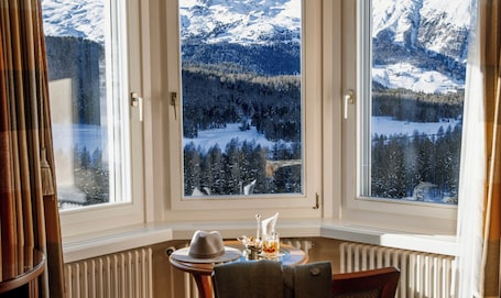 A room with a large window offering a view of a snowy mountain landscape.