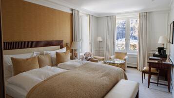 Une chambre d’hôtel avec un grand lit, un bureau, une chaise et une vue sur un paysage enneigé par la fenêtre.