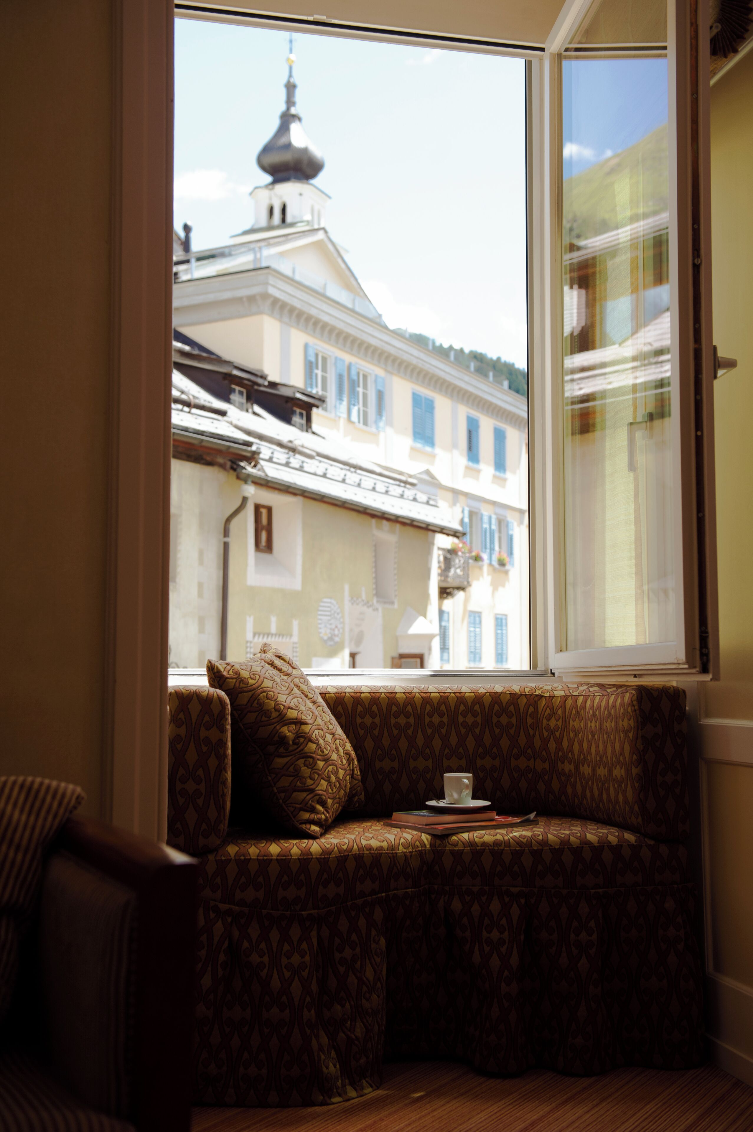 A room with a window overlooking a building with a dome and balconies.