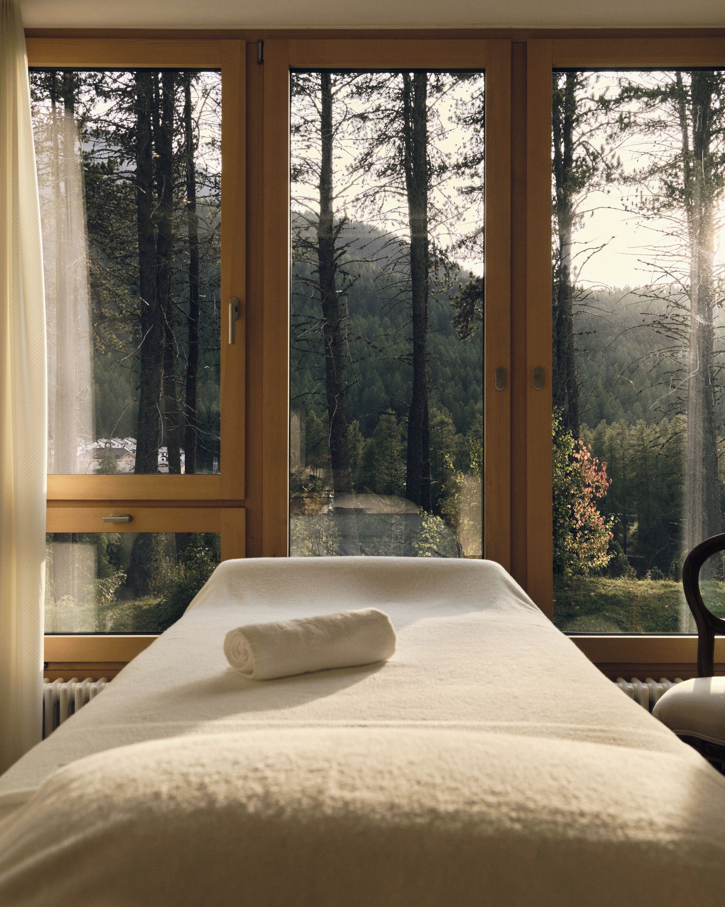 Ein Schlafzimmer mit einem Bett, einem Fenster und Blick auf einen Wald.