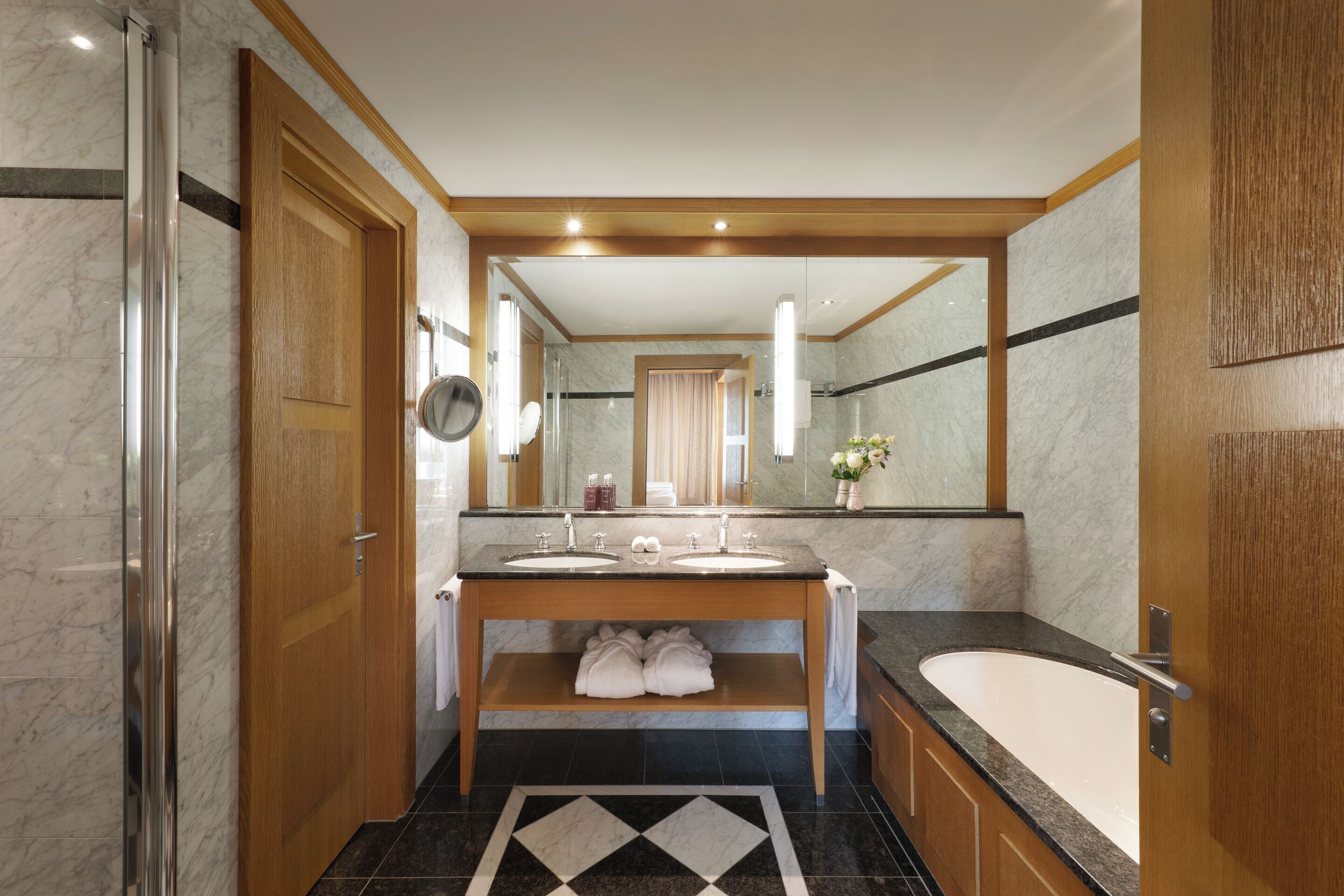 A modern bathroom with a double sink vanity, a large mirror, a bathtub, and a shower.