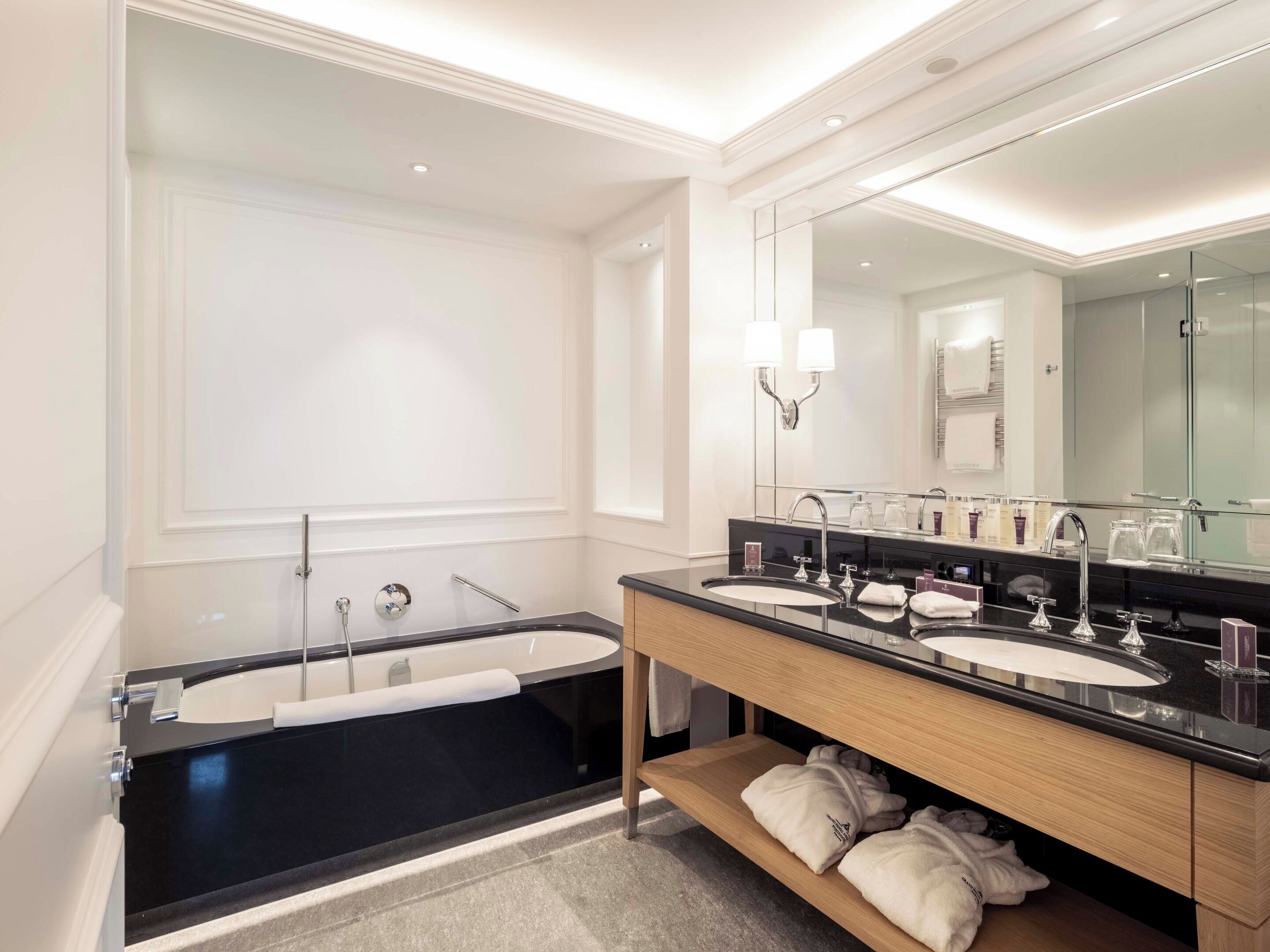 Un baño moderno con una bañera grande, dos lavamanos y un mueble de tocador con espejo.
