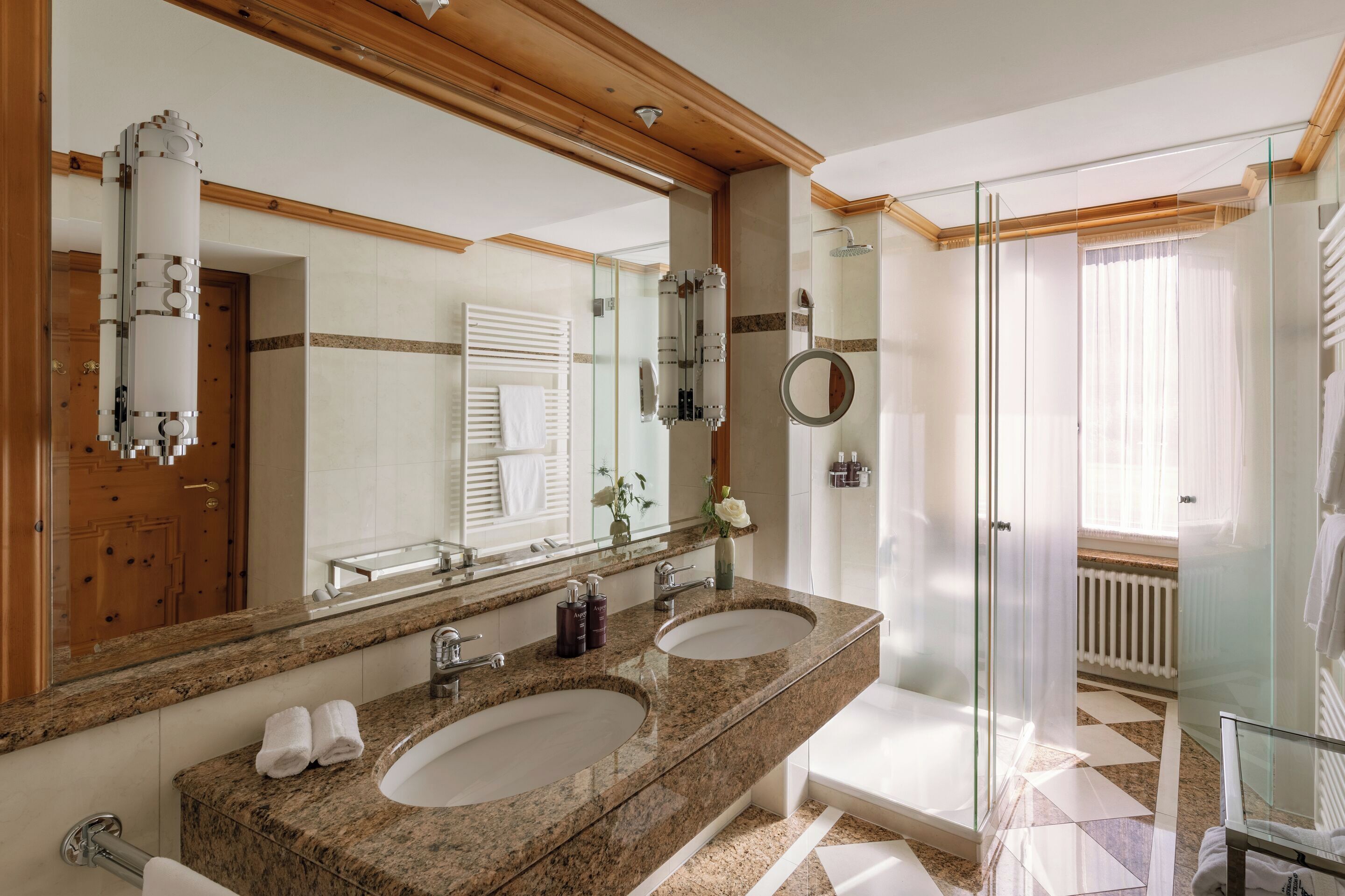 A bathroom with two sinks, a large mirror, and a shower area.