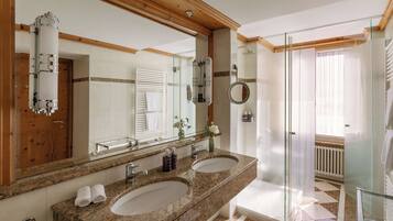A bathroom with two sinks, a large mirror, and a shower area.