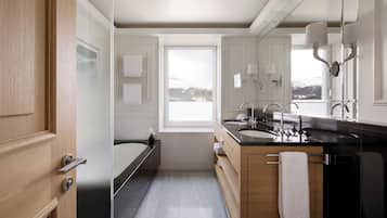 Een moderne badkamer met een badkuip, twee wastafels en een grote spiegel.