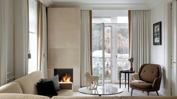 A living room with a fireplace, a sofa, a chair, and a glass table.