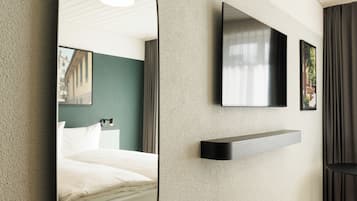 Ein modernes Hotelzimmer mit einem Bett, einem an der Wand befestigten Fernseher und einem Wandregal.