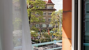 Une vue d’un bâtiment avec un toit rouge et de nombreuses fenêtres, prise à travers une fenêtre à cadre blanc.