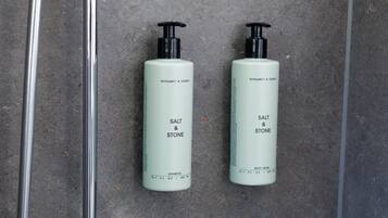 A bathroom with two bottles of shampoo and a showerhead.