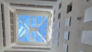 A modern interior with a central skylight, multiple windows, and a series of white panels on the walls. - Fred Hotel Central (Zürich)