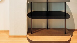 A corner room with a round black table, a wooden hanger, and two round wall decorations.