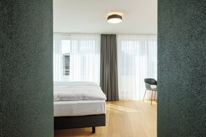 A modern hotel room with a bed, a chair, and a view of the outside. - Fred Hotel Central (Zürich)