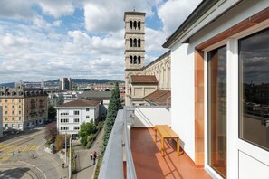 Un balcón con vistas a un paisaje urbano, incluyendo una torre y varios edificios.