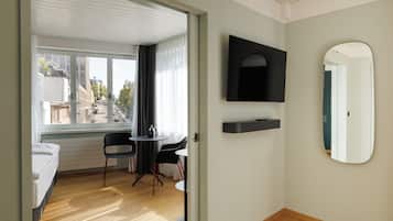 Une chambre d’hôtel avec un lit, une petite table avec des chaises, une télévision et un miroir.