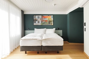 A modern bedroom with a bed, a nightstand, and a wall-mounted picture.