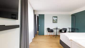 Habitación de hotel con cama, televisión, escritorio y sillas, y un cuadro en la pared.