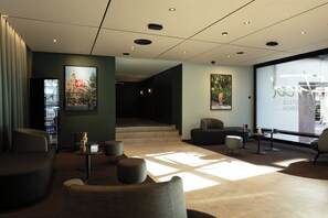 A modern lobby with a seating area, a staircase, and artwork on the walls. - Fred Hotel Central (Zürich)